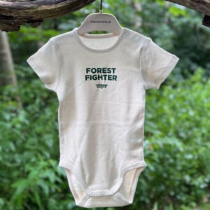 Baby body tøj Forest Fighter i naturfarvet stof med grønt tryk hænger på en bøjle i skoven