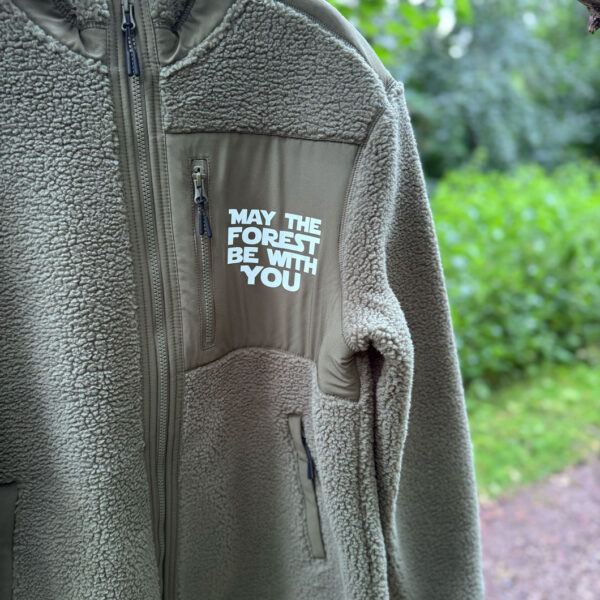 Nærbillede af fleecetrøje dame herre med brystlomme, lynlås og hvidt “May the Forest Be With You”-tryk