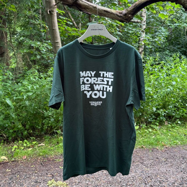 Grøn T-shirt med hvidt “May the Forest Be With You”-tryk og Verdens Skoves logo foran - vist hængende på en gren i skoven
